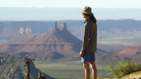 young man with long curly hair enjoys castle valley view, moab canyon