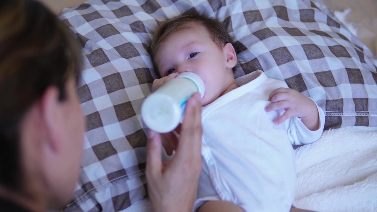 Una madre che dà latte artificiale al bambino