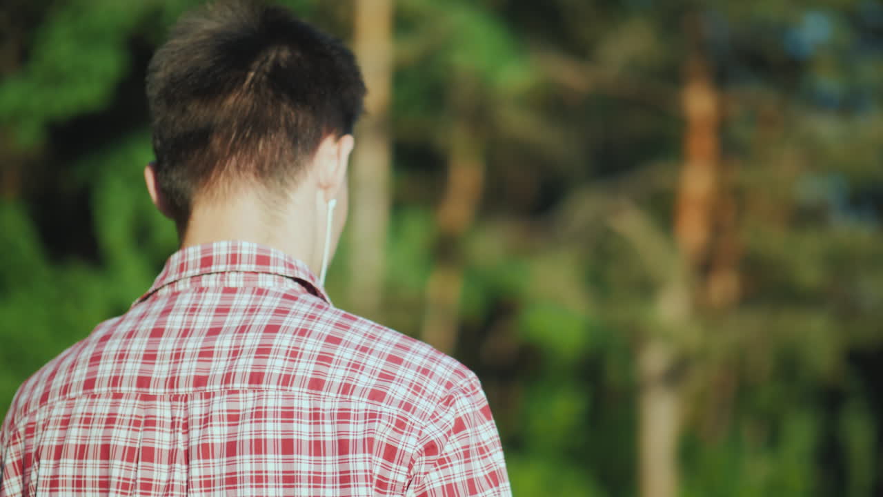 10대 청소년이 헤드폰으로 음악을 들으며 공원을 산책하고 있습니다.