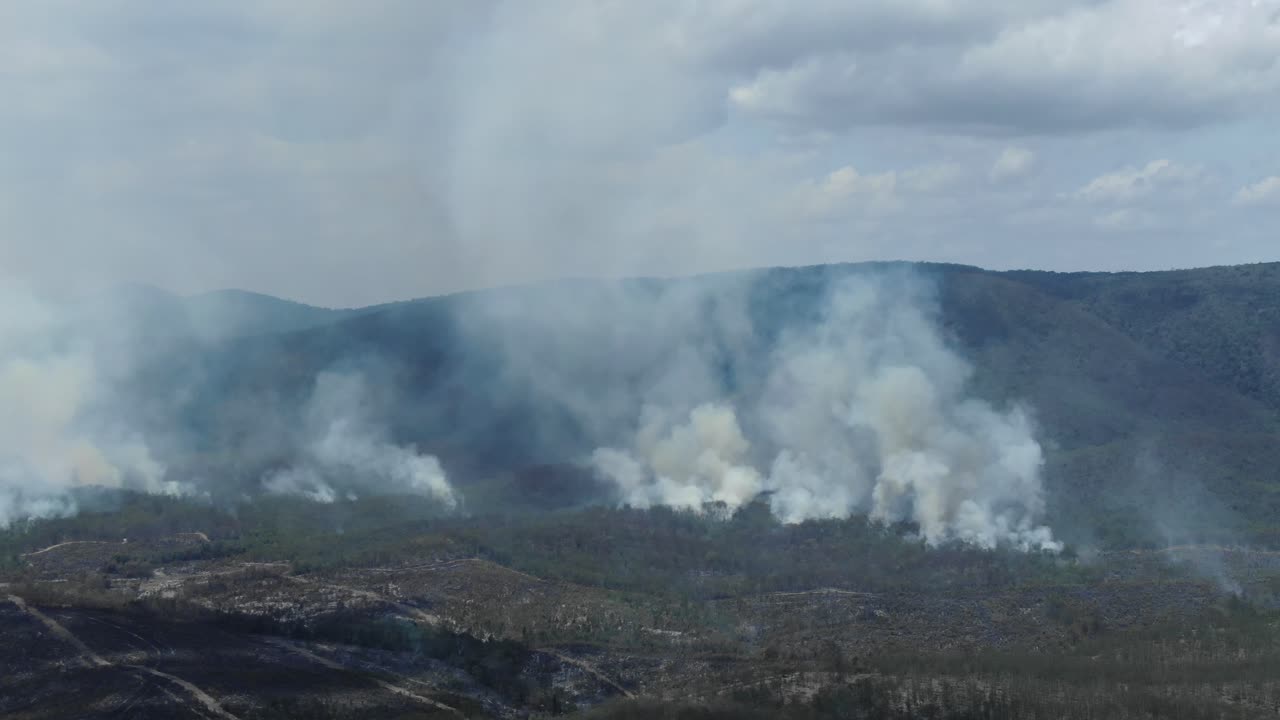 Smoke columns over Queensland mountains in Australia. Aerial drone forward pov
