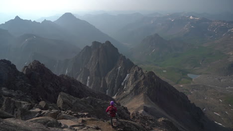 lonely climber with backpack on mountain peak above stunning misty valley on sunny day