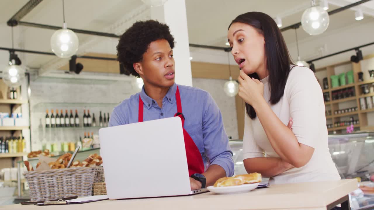 video de una mujer propietaria y un camarero trabajando con una computadora portátil en una cafetería