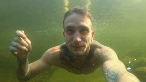 a young man films himself with an action camera as he swims through the dark, gloomy and murky the cold norwegian water