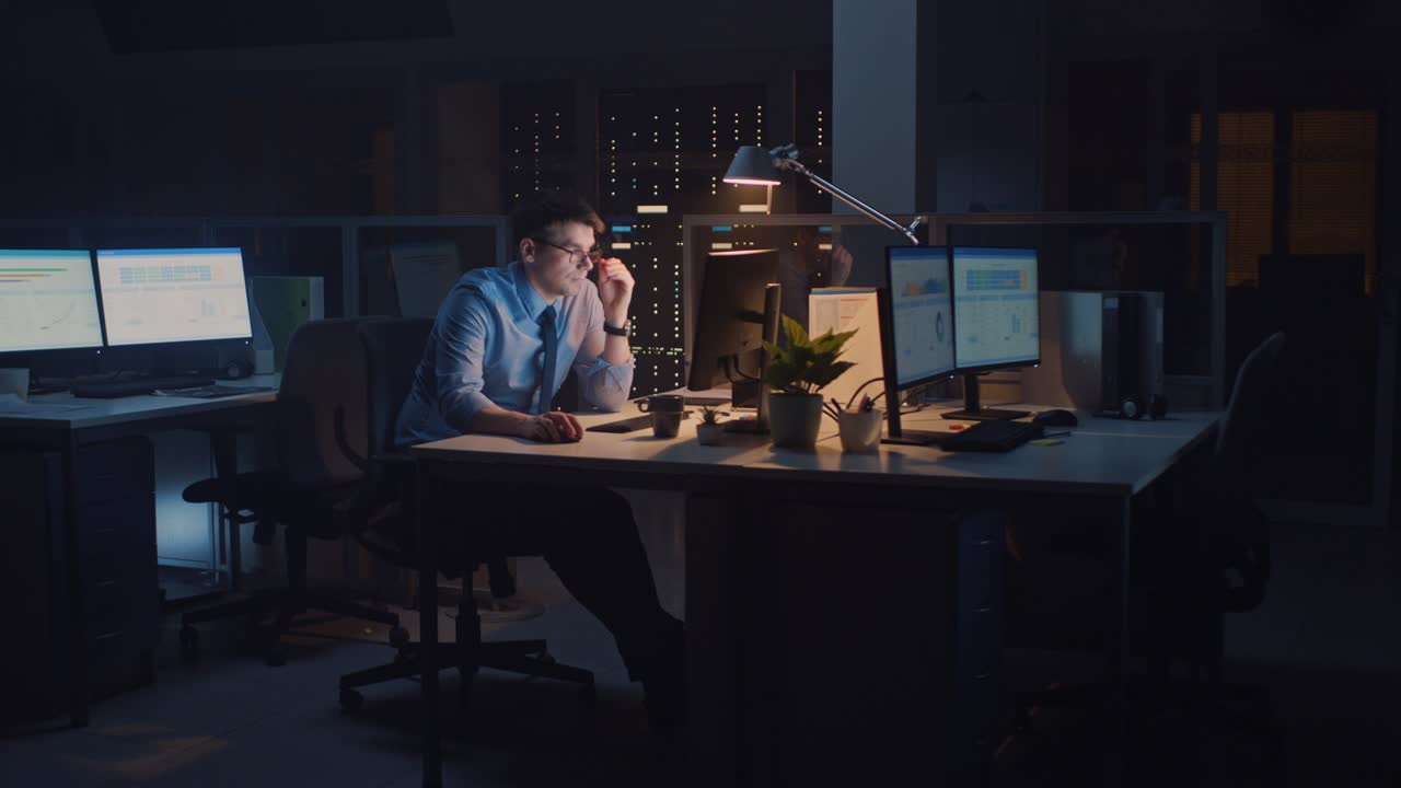In the Office at Night, Overworked Tired Office Worker Uses Desktop Computer but Falls Asleep Fast. Tired Frustrated Exhausted Businessman Falls asleep at His Job