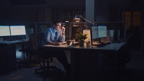 in the office at night, overworked tired office worker uses desktop computer but falls asleep fast. tired frustrated exhausted businessman falls asleep at his job