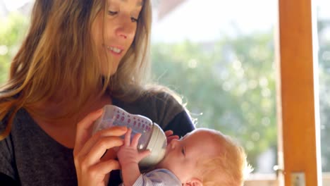 mother feeding milk to her baby boy in living room 4k