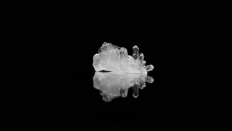 crystal clear quartz glistening under studio lighting on black background, captured through smooth zoom-in dolly