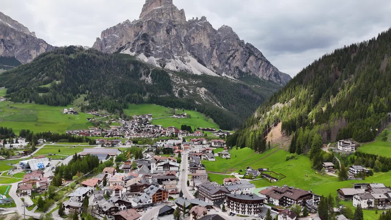 Corvara village nestled in the Dolomites with a towering rocky peak and green valley