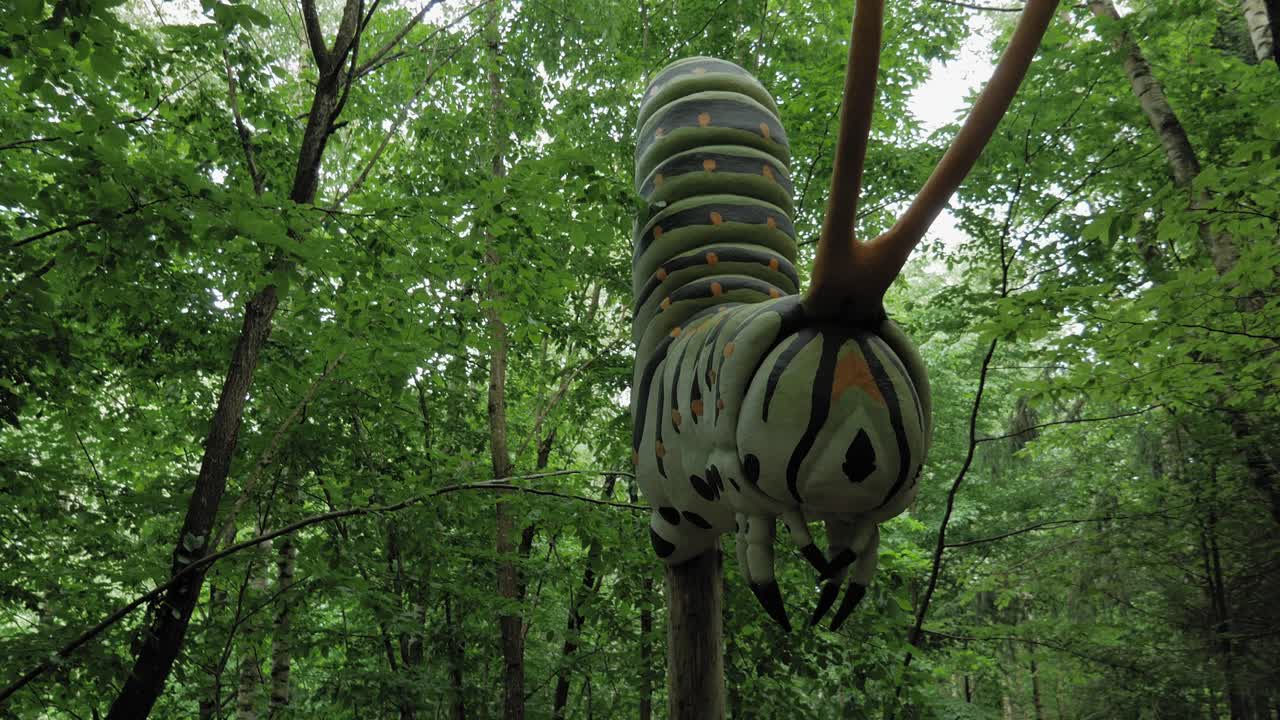 gran modelo de oruga contra los árboles verdes en el bosque en el parque de gigantes kashubian, strysza buda, polonia