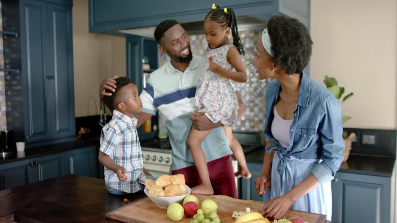 Happy african american family talking and cooking in kitchen, in slow motion