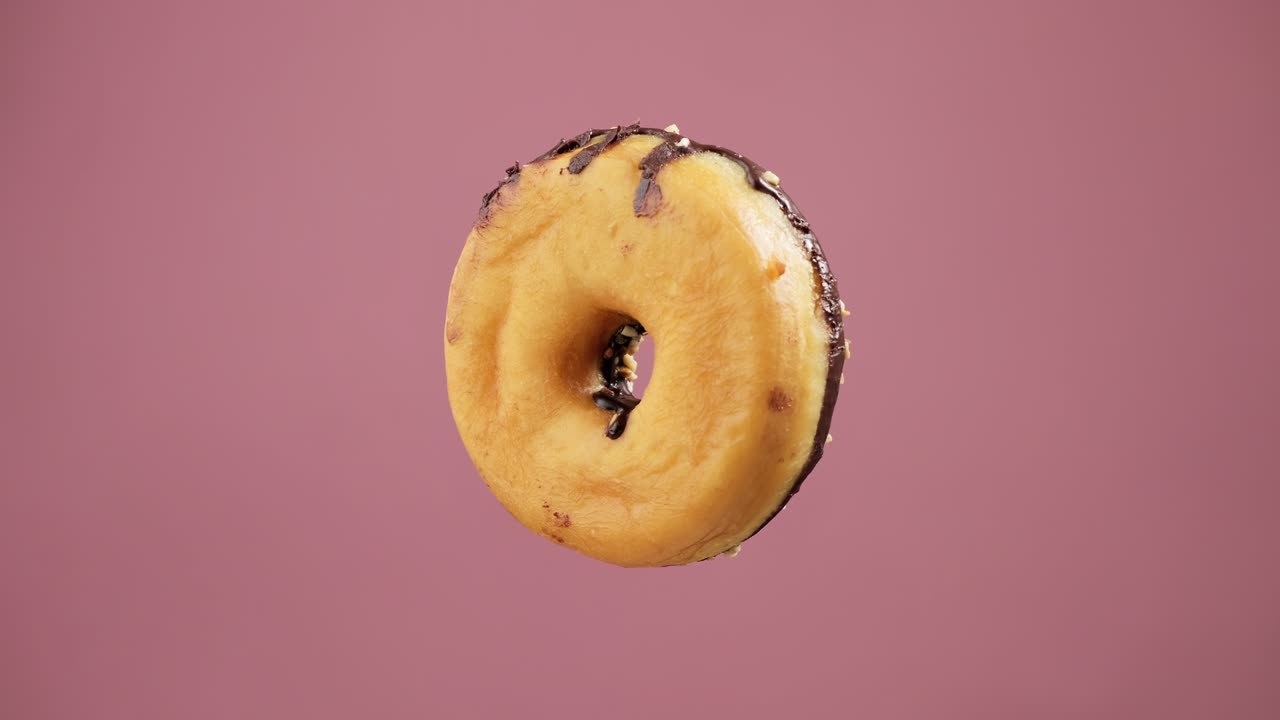 el donut de chocolate girando en el fondo rosa. el postre dulce volador.