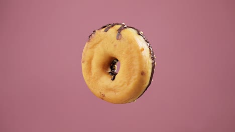 chocolate donut rotating at pink background. flying sweet dessert.