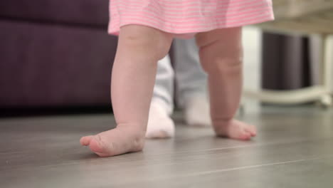 little baby learning walk on floor. infant doing first steps with father