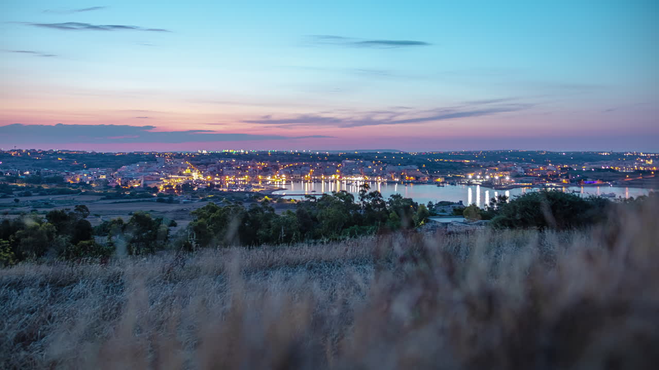 High angle shot of seaside town houses in Marsaxlokk, Malta from night to morning time in timelapse