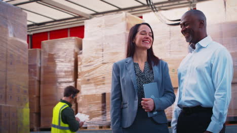 portrait of male and female freight haulage managers standing by lorry being loaded with boxes
