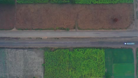 Vista-Aérea-De-Pájaro-Sobre-La-Autopista-A-Través-De-Las-Tierras-De-Cultivo-De-Sindh-Con-El-Tráfico-Pasando