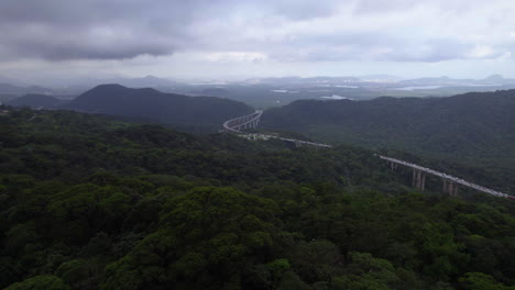 aerial view flying over forest towards the santos highway in mata atlantica, cloudy brazil