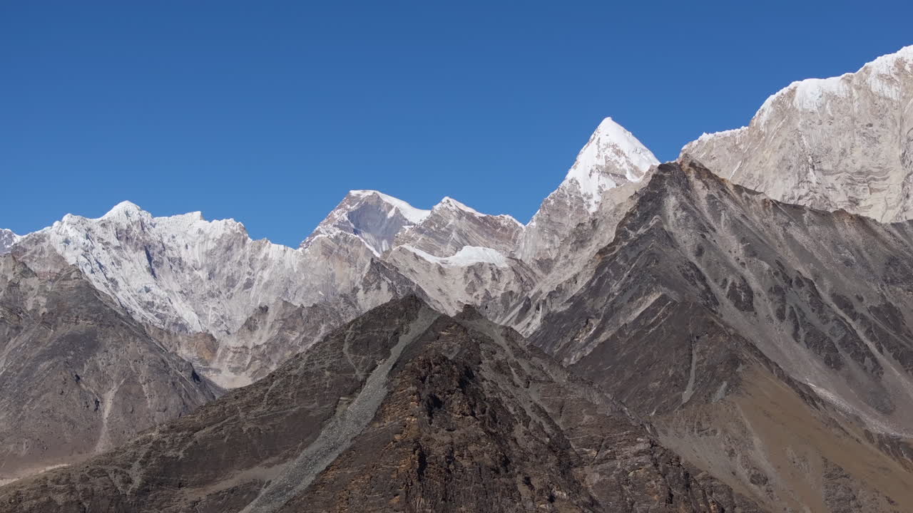 Ripresa con drone in planata attraverso il terreno montano arido nella regione dell'Everest in Nepal, che evidenzia la diminuzione della neve e i cambiamenti ambientali legati al riscaldamento globale sull'Himalaya.