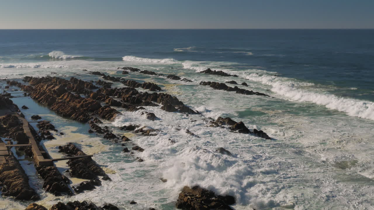 vista desde el punto de vista alto de la costa rocosa con olas rompiendo en el punto de mosselbay, sudáfrica
