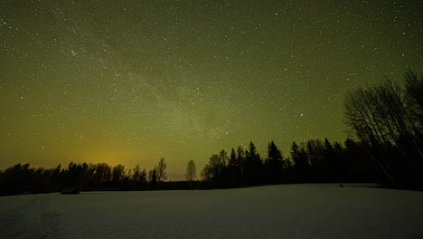 magical time-lapse of the colorful night sky filled with clear stars moving above a snowy winter forest