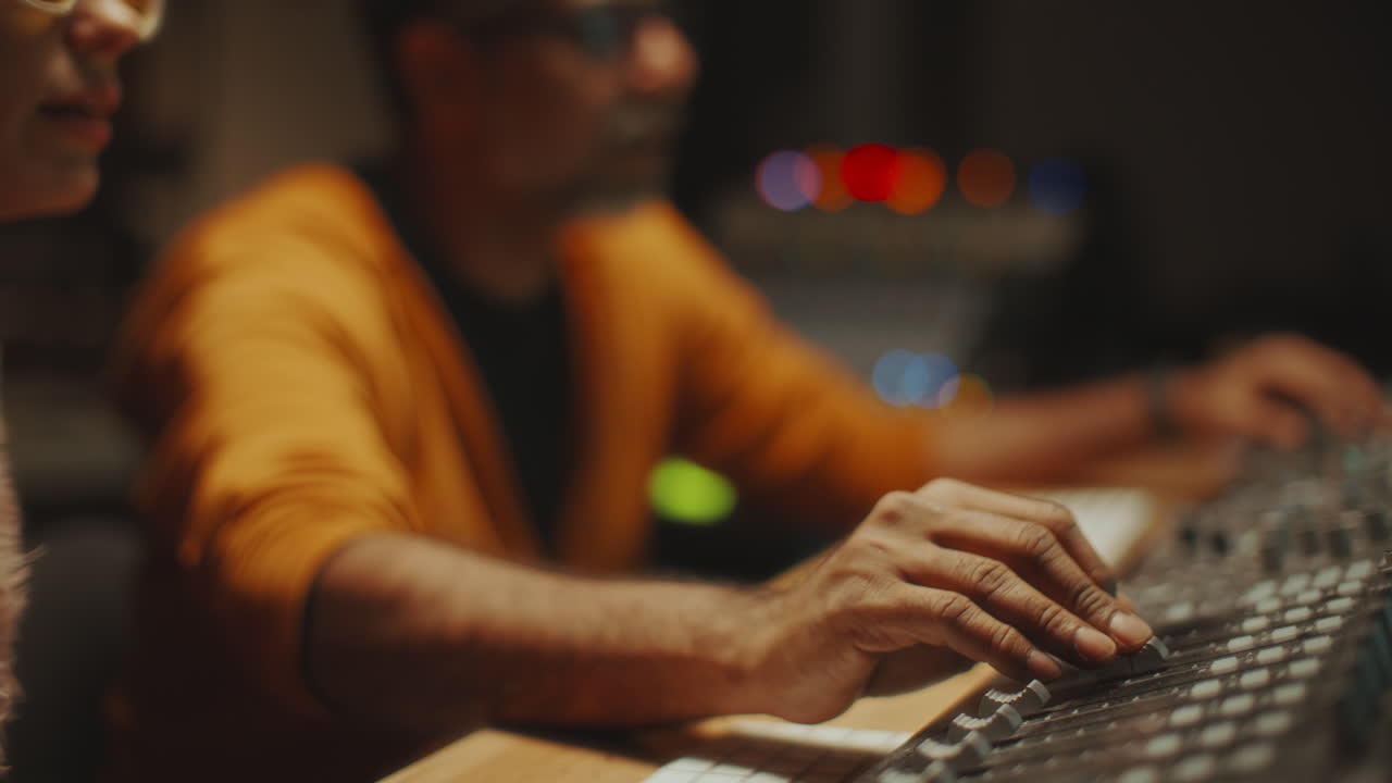 Sound Engineer Adjusting Levels on Mixing Console as Working with Musician