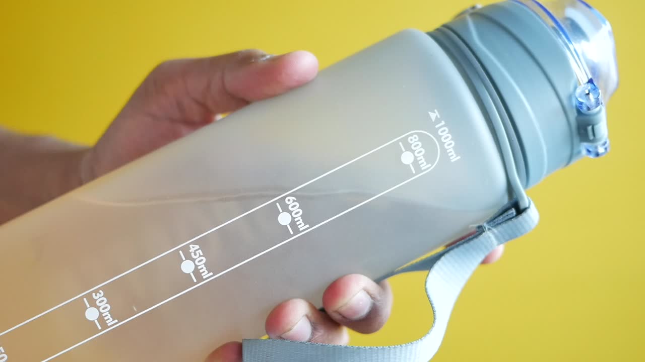 persona que sostiene una botella de agua gris