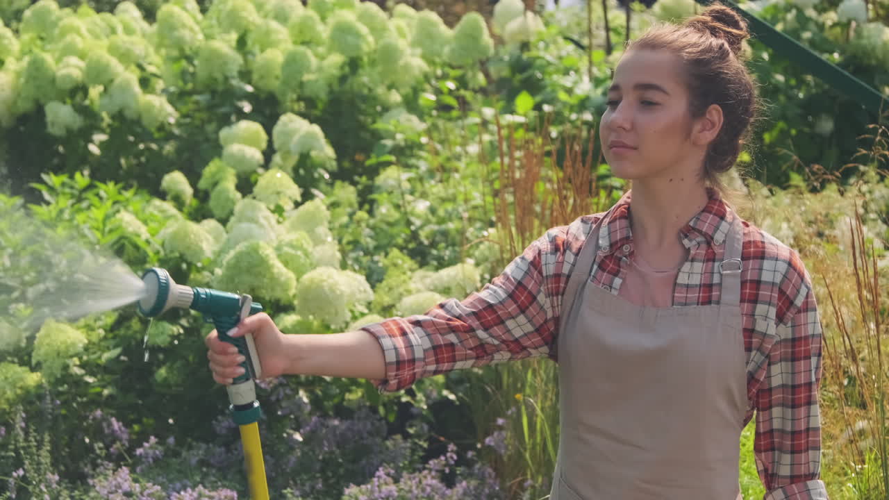 Woman watering garden flowers with hose