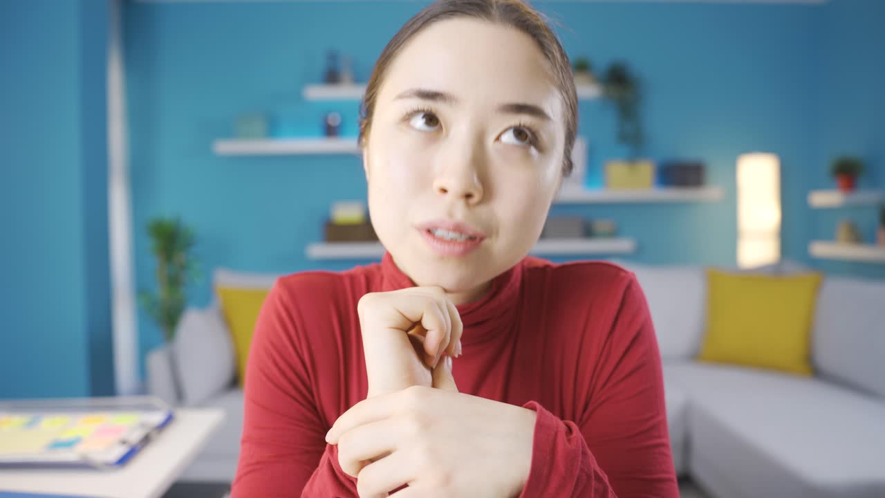 아시아 여성이 생각하고 주변을 둘러보며 무언가를 생각하고 있습니다.