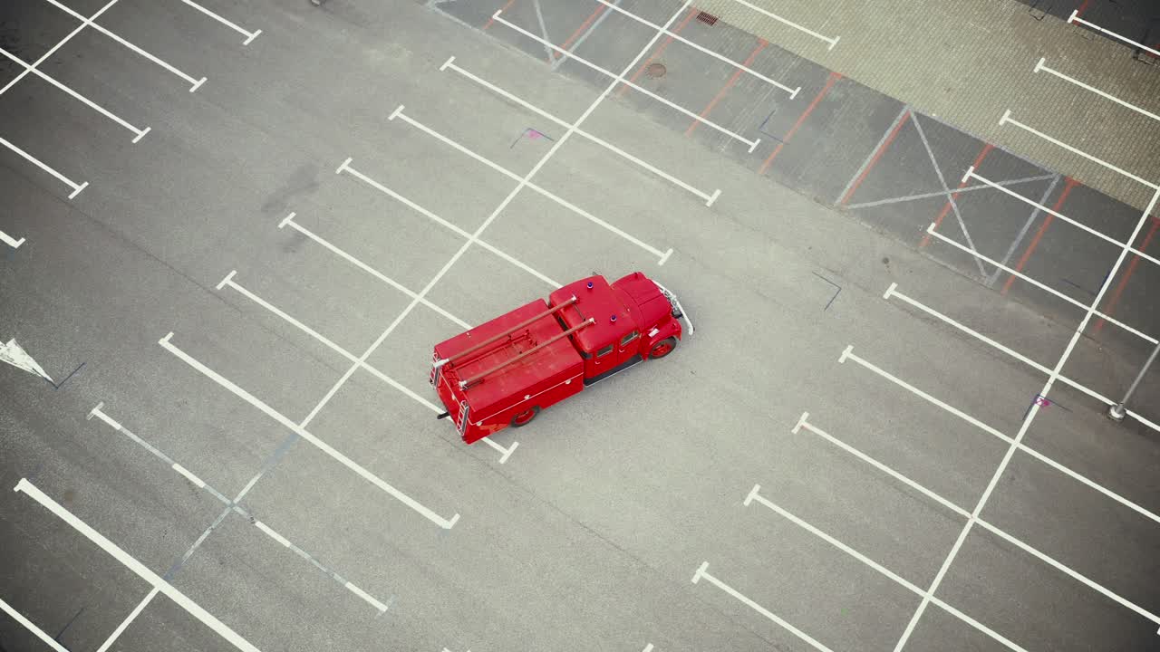 Vintage red vehicle, old fire engine equipped with tools for firefighting tasks, driving on empty parking