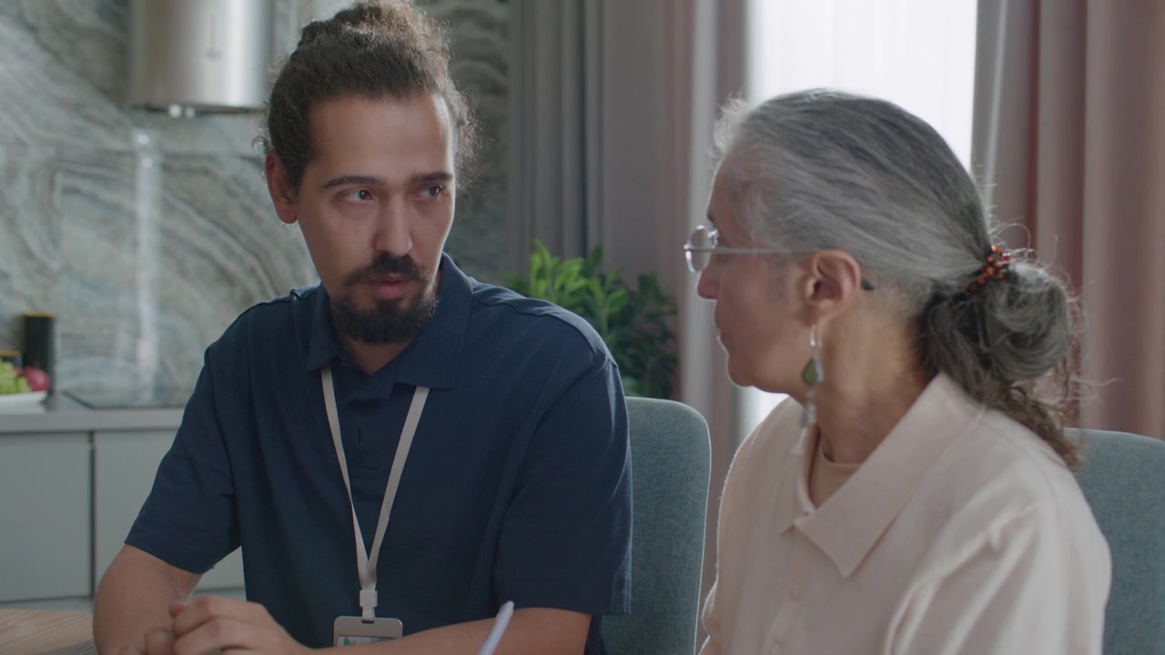 Donna anziana che firma una bolletta con l'aiuto di un assistente domiciliare