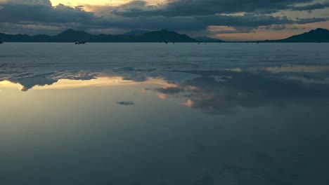 Sideway-aerial-of-a-reflection-of-the-mountain-and-lake-bed-landscape-on-the-water