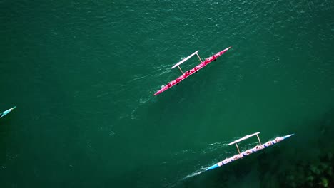 beautiful aerial over a red outrigger canoe paddled on blue water