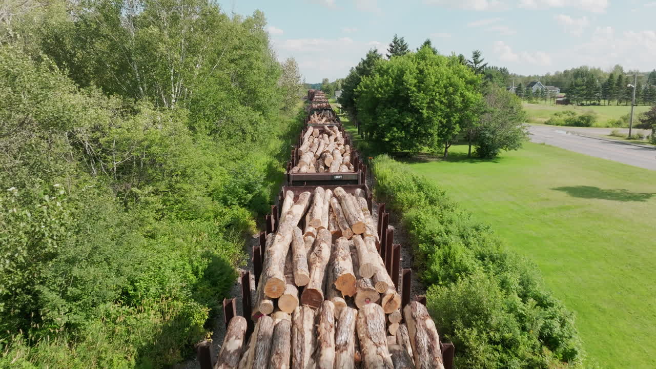 Close Aerial View of Freight Train Carrying Lumber Through Rural Maine