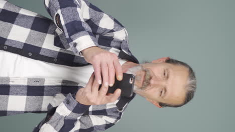 Vertical-video-of-Dancing-old-man-with-phone-in-hand.