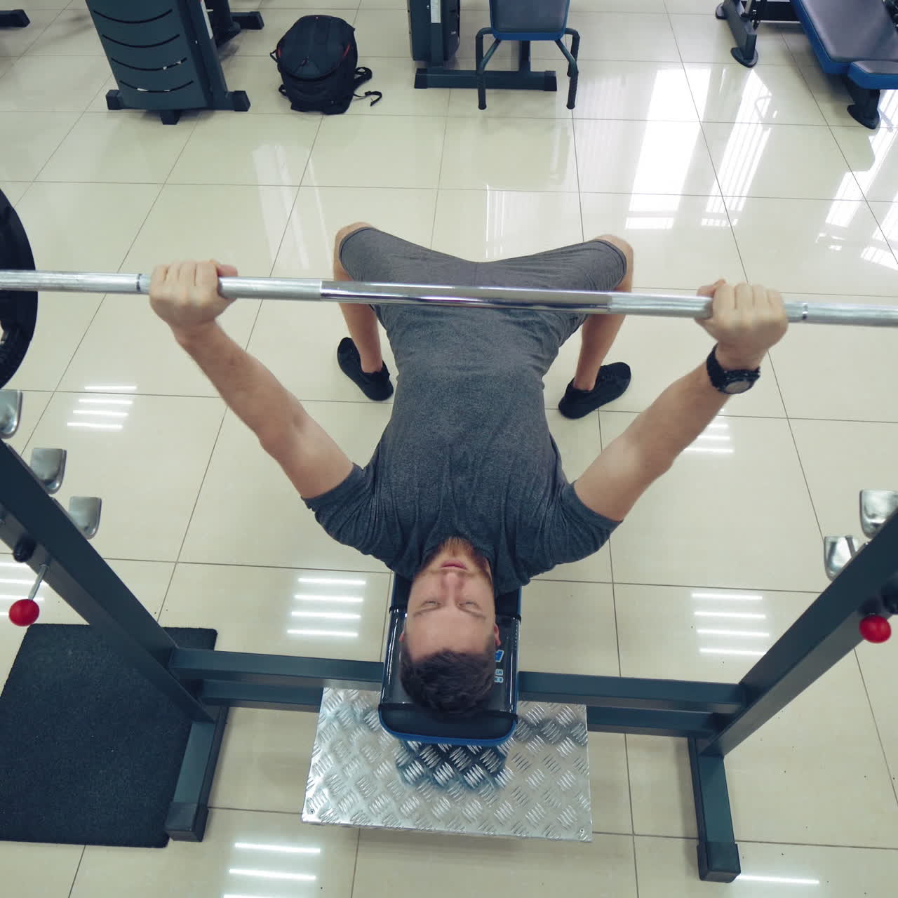 Handsome Man Is Working Out Chest With Barbell In A Modern Gym