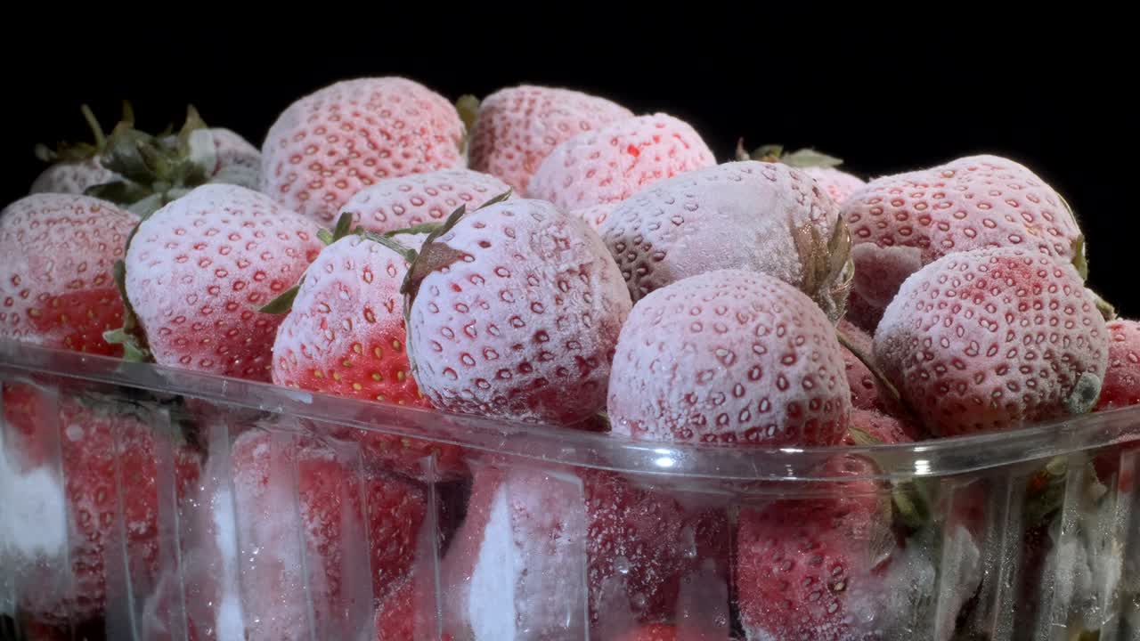 흑색 바탕의 일회용 플라스틱 식품 패키지에 담긴 신선한 냉동 딸기, 360도 회전, 클로즈업