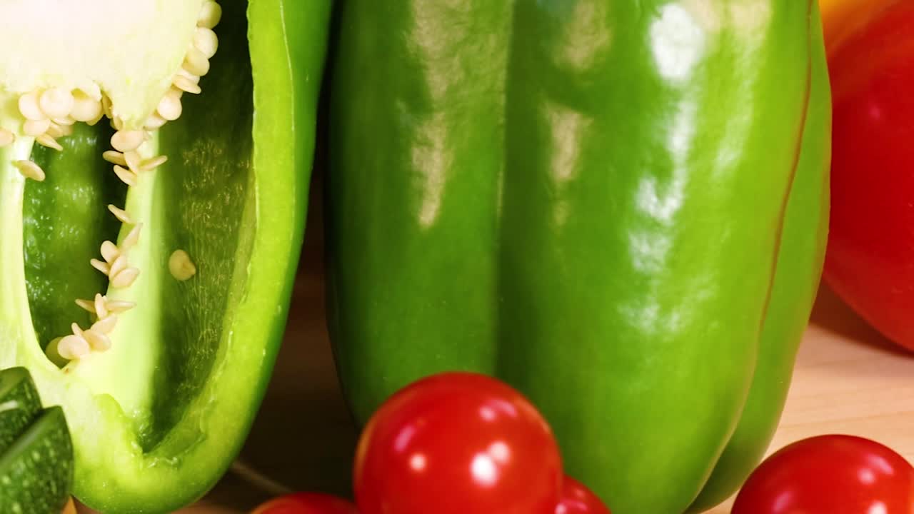 A colorful arrangement of zucchini, green peppers, and cherry tomatoes on a light background.