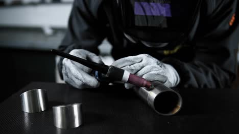 close view of a man with a blowtorch welding a steel pipe