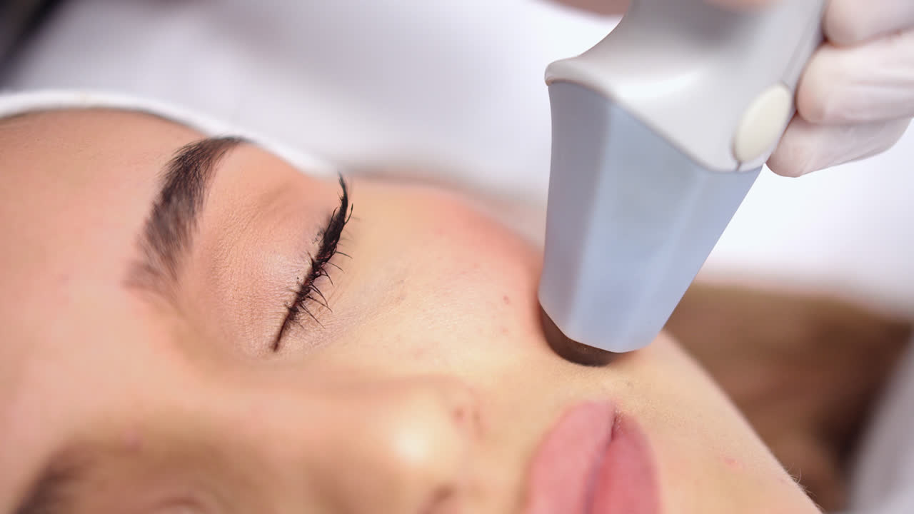 Beautiful close-up shot of the face of a young beautiful woman with clean skin receiving a beauty treatment with technological equipment in a dermatological clinic.