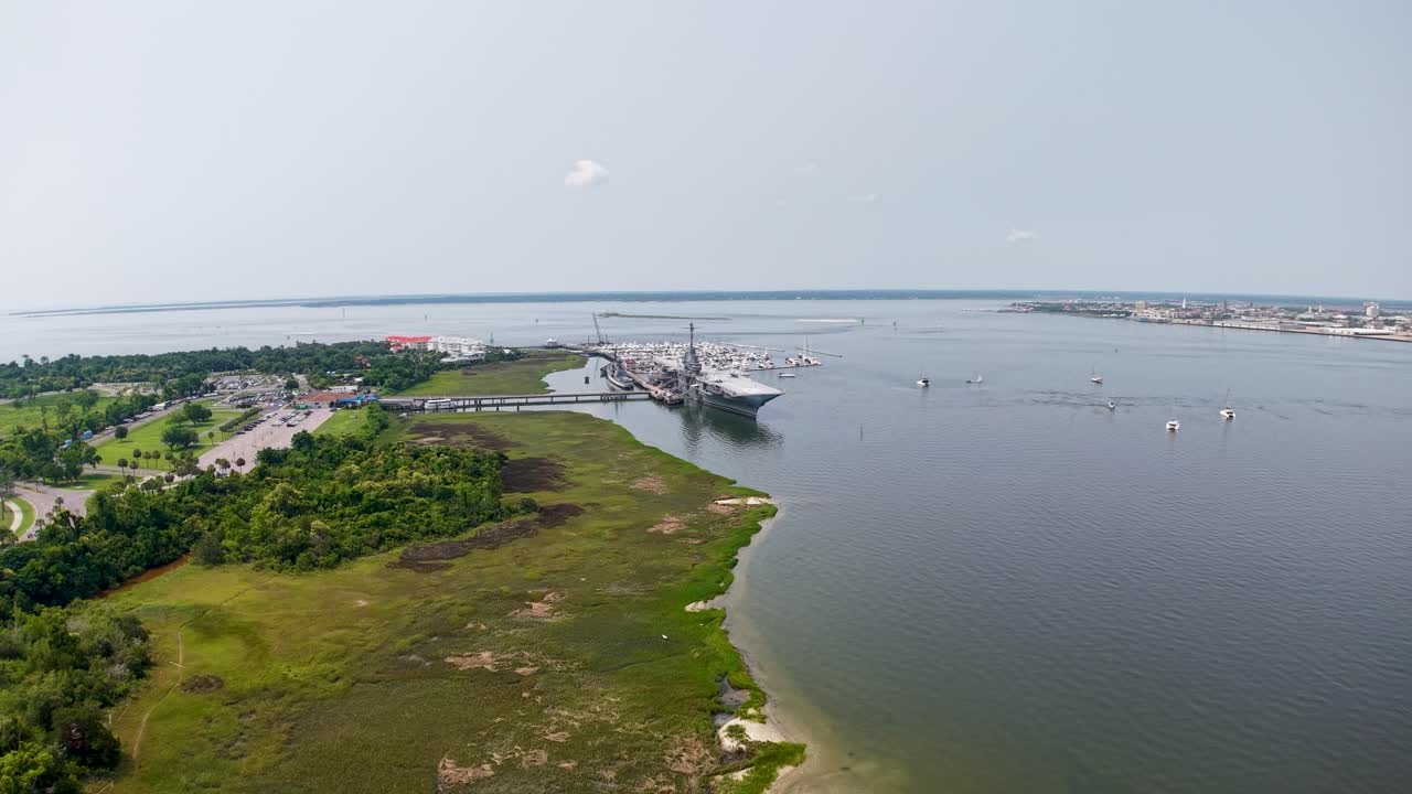Aerial drone footage over a marshy river in Charleston, South Carolina, showing green wetlands, winding shoreline and calm water under a clear sky