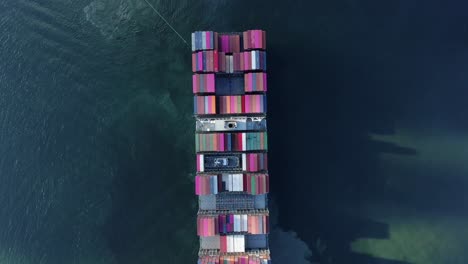 two tugboats manoeuvring a large empty container ship into hong kong port, aerial view