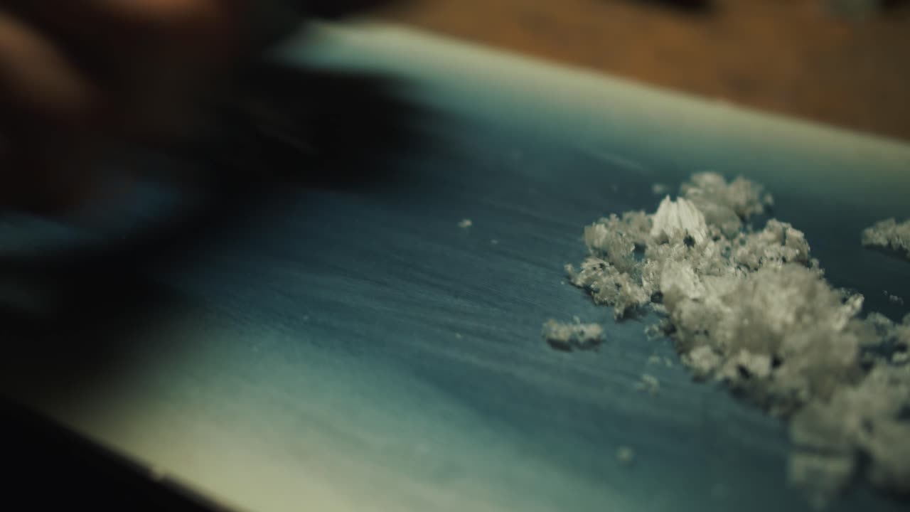 Škrábání vosku ze snowboardu.