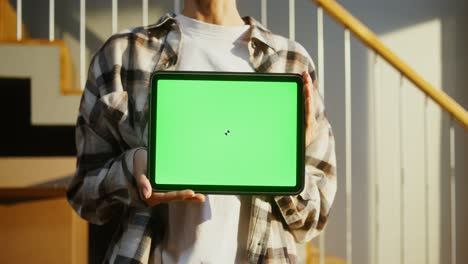 person holding a tablet with green screen display