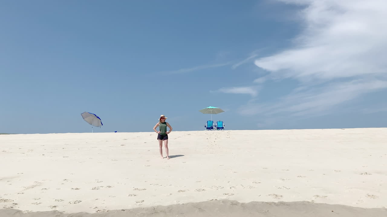 una bella mujer está sola en la playa con dos sillas y sombrillas