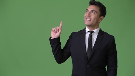 joven y guapo hombre de negocios hispano contra un fondo verde
