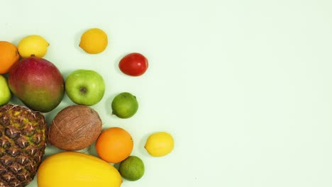 tropic summer fruits move on left side of light green background. stop motion