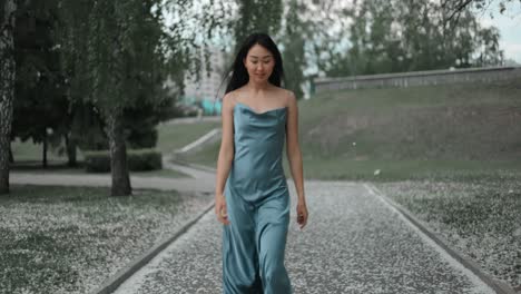 woman in a blue satin dress walking in a park