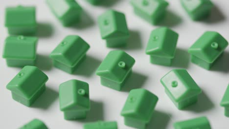 Home-Buying-Concept-With-Group-Of-Green-Plastic-Models-Of-Houses-Revolving-On-White-Background-