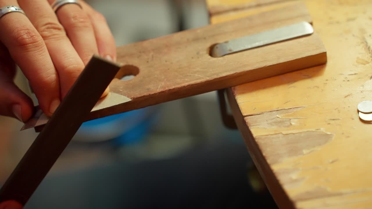 A craftsman focuses on sharpening a metal blade, using steady hands and traditional techniques in a well-lit workshop.