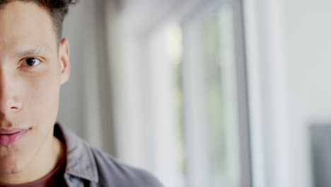 retrato de un hombre biracial feliz sonriendo en casa, en cámara lenta